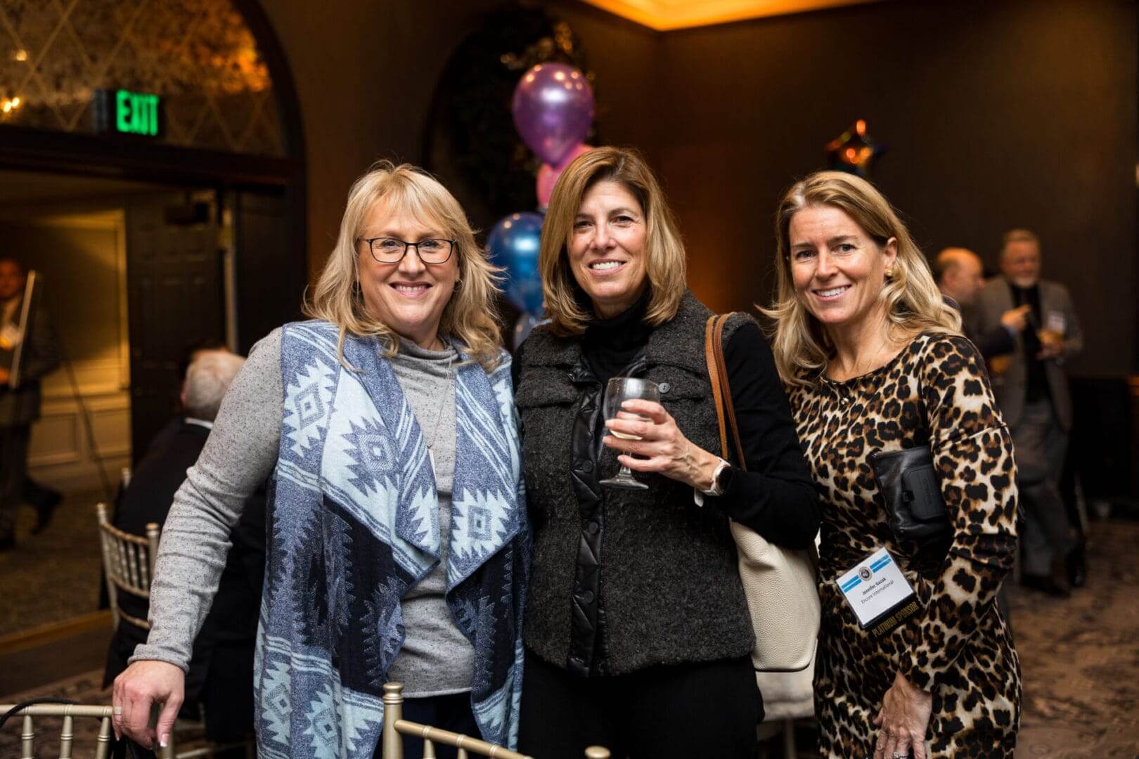 Three women smiling at a social event.