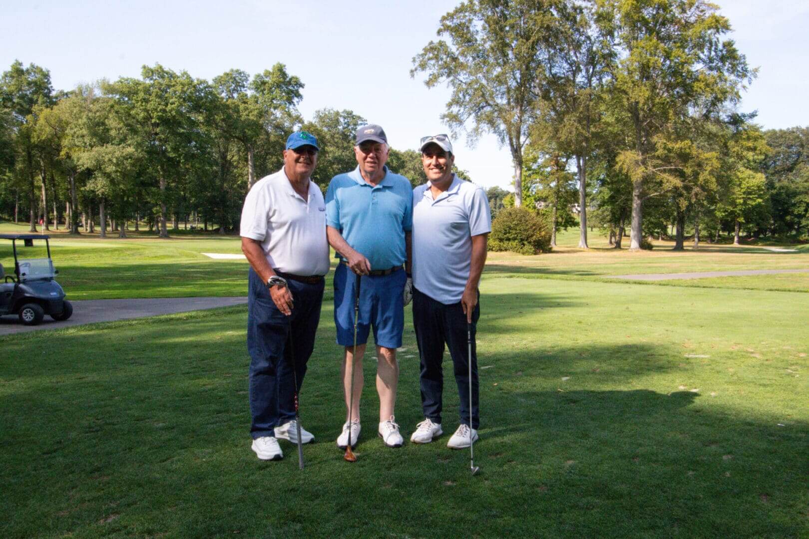 Three men standing on a golf course.