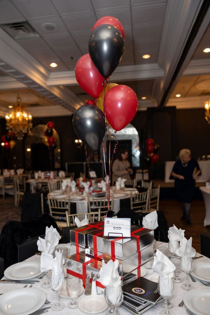 Decorated banquet table with balloons and gifts.